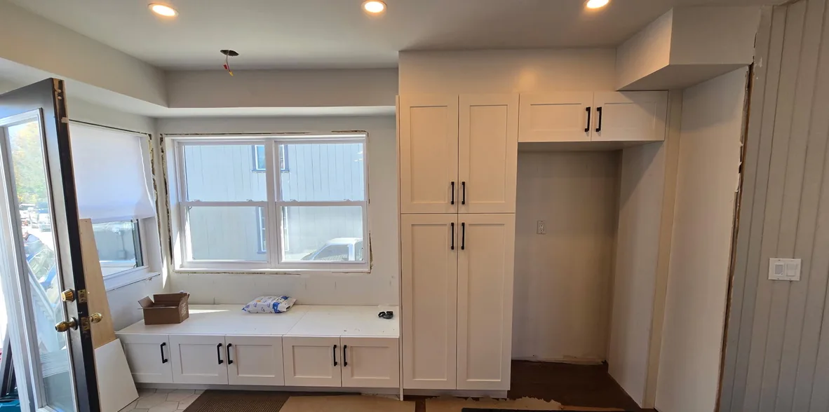 A white window bench with five doors and black handles, a tall pantry and a cabinet over the fridge niche, Schomberg Ontario