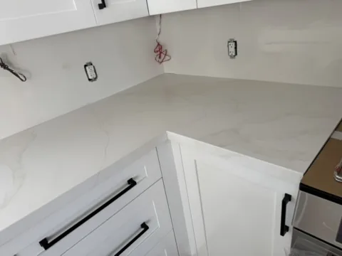 White quartz with soft grey veining turning the corner over white shaker drawers with black handles, Schomberg Ontario