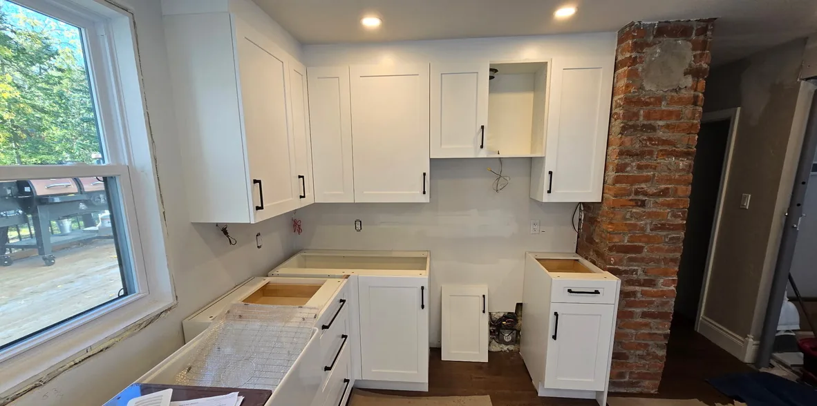 White shaker cabinets installed on the range wall next to the exposed brick chimney, before the counters, Schomberg Ontario