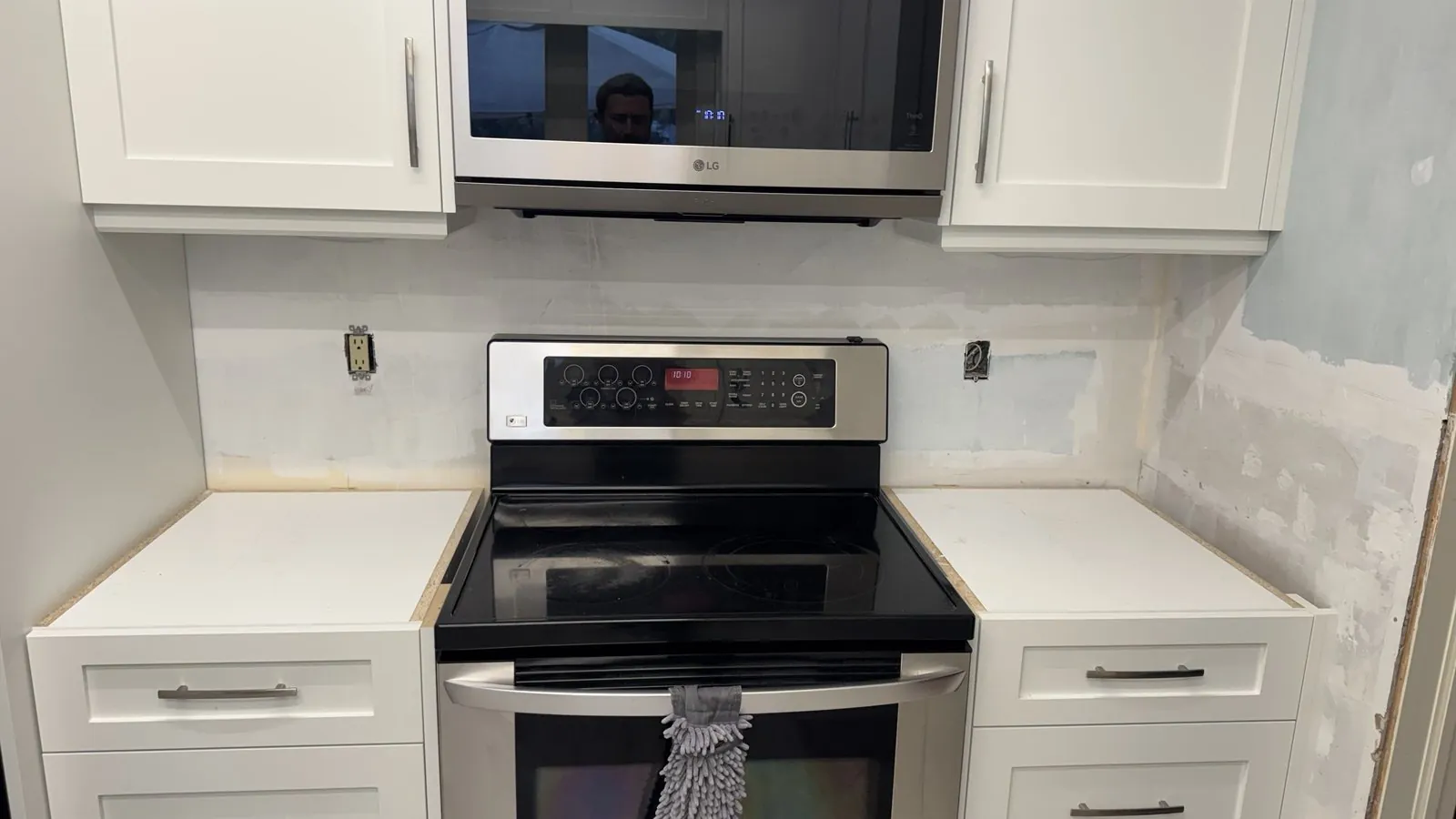 New white shaker base cabinets with bare tops on either side of an electric range, unfinished drywall behind, Whitchurch-Stouffville Ontario