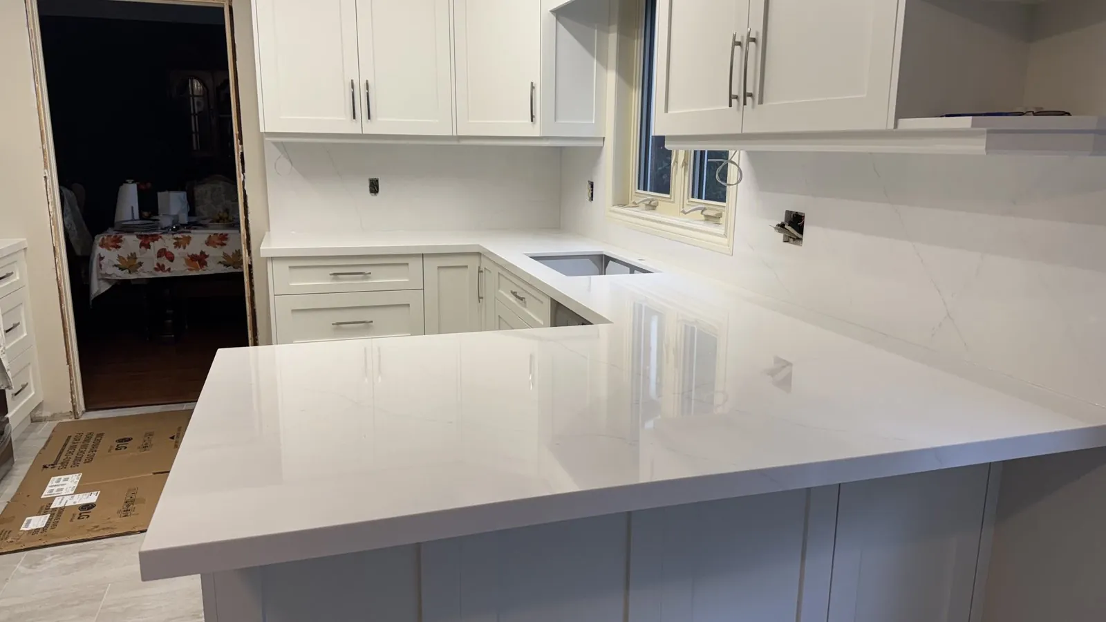 The same kitchen with Viatera Velo white quartz on the counters and peninsula, an undermount sink and a full-height quartz backsplash around the window, Whitchurch-Stouffville Ontario