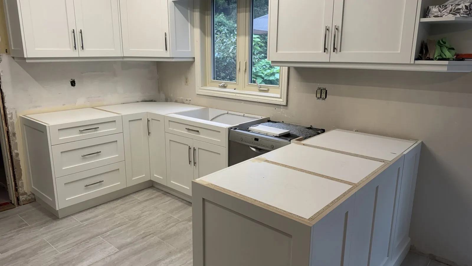 New white shaker base cabinets and a peninsula with bare particleboard tops and an empty sink base, before countertops, Whitchurch-Stouffville Ontario
