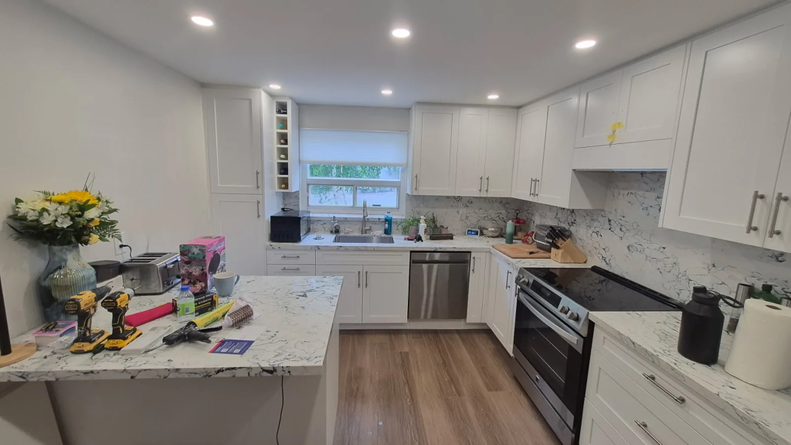 White shaker kitchen with a quartz peninsula, an undermount sink under the window, a wine rack beside the tall cabinet and a full-height quartz backsplash, Aurora Ontario